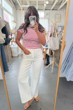 Load image into Gallery viewer, Person taking a mirror selfie wearing a striped shirt and white pants in a clothing store.