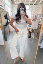 Load image into Gallery viewer, Person taking a mirror selfie wearing a striped shirt and white pants in a clothing store.