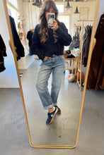 Load image into Gallery viewer, Person taking a mirror selfie wearing a dark sweater, light jeans, and black shoes in a clothing store.