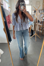 Load image into Gallery viewer, Woman taking a mirror selfie wearing a light blue top and jeans in a store.