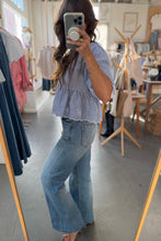 Load image into Gallery viewer, Person taking a mirror selfie wearing a light blue top and jeans in a clothing store.