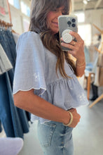 Load image into Gallery viewer, Person taking a mirror selfie wearing a blue and white striped top with ruffled sleeves in a clothing store.