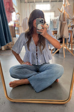 Load image into Gallery viewer, Person taking a mirror selfie wearing a light blue shirt and jeans in a casual setting.