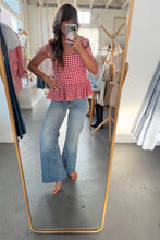 Load image into Gallery viewer, Person taking a mirror selfie wearing a red checkered top and blue jeans in a clothing store.
