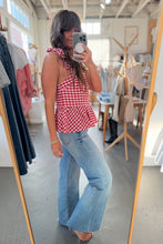 Load image into Gallery viewer, Woman taking a mirror selfie wearing a red checkered top and blue jeans in a clothing store.