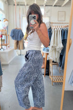 Load image into Gallery viewer, Person taking a mirror selfie wearing a white top and blue patterned pants in a clothing store.
