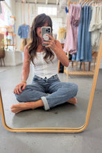 Load image into Gallery viewer, Woman taking a mirror selfie in a clothing store, wearing a white blouse and blue jeans.