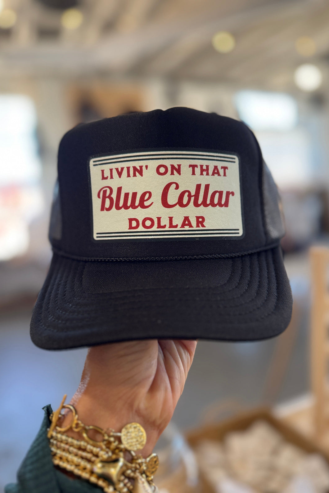Black cap with 'Livin' on that Blue Collar Dollar' text held by a person.