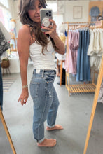 Load image into Gallery viewer, Woman taking a mirror selfie wearing a white tank top and blue jeans in a clothing store.