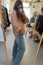 Load image into Gallery viewer, Person taking a mirror selfie wearing a striped shirt and jeans in a clothing store.