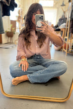 Load image into Gallery viewer, Person sitting on the floor taking a mirror selfie wearing a striped shirt and jeans.