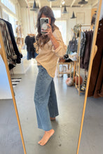 Load image into Gallery viewer, Person taking a mirror selfie wearing a striped shirt and wide-leg jeans in a clothing store.