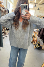 Load image into Gallery viewer, Person wearing a gray sweater and blue jeans taking a mirror selfie in a clothing store.