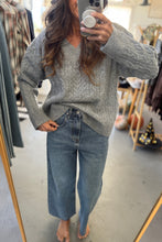 Load image into Gallery viewer, Person wearing a gray sweater and blue jeans in a clothing store.
