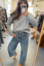 Load image into Gallery viewer, Person wearing a gray sweater and blue jeans in a clothing store.