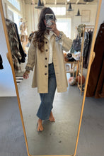 Load image into Gallery viewer, Person wearing a beige trench coat in a clothing store.
