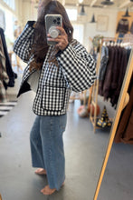 Load image into Gallery viewer, Person wearing a black and white checkered jacket and blue jeans in a clothing store.