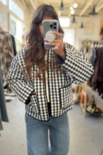 Load image into Gallery viewer, Person wearing a black and white checkered jacket in a clothing store.