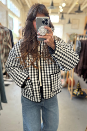 Person wearing a black and white checkered jacket in a clothing store.