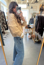 Load image into Gallery viewer, Person taking a mirror selfie wearing a beige sweater and blue jeans in a clothing store.