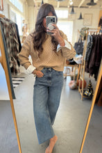 Load image into Gallery viewer, Woman taking a mirror selfie wearing a beige sweater and blue jeans in a clothing store.