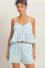 Load image into Gallery viewer, Woman wearing a light blue peplum top and shorts set on a beige background