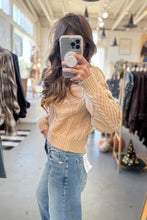 Load image into Gallery viewer, Person wearing a beige sweater and blue jeans in a clothing store.