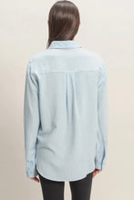 Load image into Gallery viewer, Light blue shirt worn by a person on a beige background