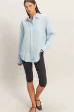 Load image into Gallery viewer, Woman wearing a light blue shirt and black capri pants on a plain background