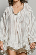 Load image into Gallery viewer, Woman wearing a long-sleeve, ruffled blouse with a neutral color palette on a plain background