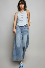 Load image into Gallery viewer, Woman wearing a light blue sleeveless top and wide-leg jeans against a gray background