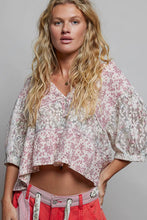 Load image into Gallery viewer, Woman wearing a floral blouse and red pants against a gray background