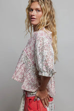 Load image into Gallery viewer, Woman wearing a floral blouse and red pants against a gray background