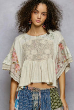Load image into Gallery viewer, Woman wearing a floral and lace top with colorful pants against a gray background