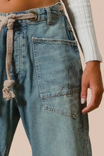 Load image into Gallery viewer, Blue denim pants with a rope tie detail on a beige background