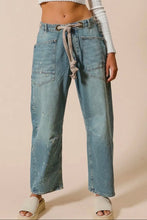 Load image into Gallery viewer, Light blue denim pants with a tie waist worn by a person on a beige background