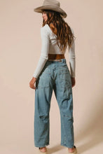 Load image into Gallery viewer, Woman wearing a white ribbed long-sleeve top and blue jeans with a beige hat against a beige background