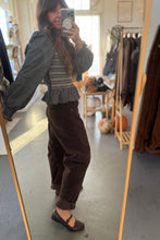 Load image into Gallery viewer, Person taking a mirror selfie wearing a patterned top and brown pants in a clothing store.