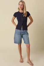 Load image into Gallery viewer, Woman wearing a navy top and denim shorts against a beige background