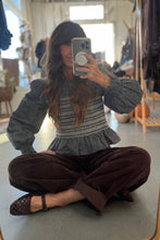 Load image into Gallery viewer, Person taking a mirror selfie wearing a textured gray sweater and brown pants in a room with furniture.