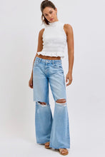 Load image into Gallery viewer, Woman wearing a white sleeveless top and light blue ripped flared jeans on a white background