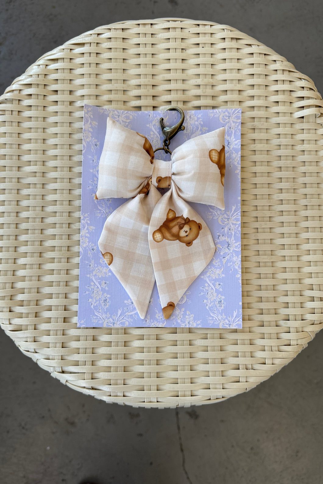 Set of hair bows with teddy bear design on a card, placed on a woven mat.