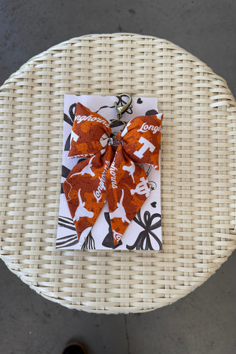 Keychain with patterned design on a card, placed on a woven mat.