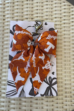 Load image into Gallery viewer, Two fabric bows with &#39;Longhorns&#39; branding on a card with decorative elements, placed on a woven surface.