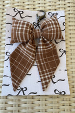 Load image into Gallery viewer, Brown plaid hair bow on a white card with black designs, placed on a woven surface.