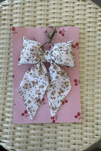 Load image into Gallery viewer, Floral-patterned keychain on a pink card with cherry designs, placed on a woven surface.