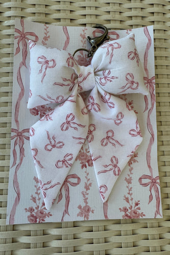 Fabric bow with pink ribbons on a matching fabric background on a woven surface