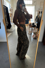 Load image into Gallery viewer, Person taking a mirror selfie wearing a brown top and camouflage pants in a store.