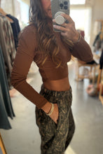 Load image into Gallery viewer, Person wearing a brown long-sleeve top and camouflage pants in a clothing store.