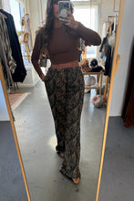 Load image into Gallery viewer, Person taking a mirror selfie wearing a brown top and patterned pants in a clothing store.